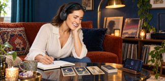 Madonna’s Mystical Eras: Tarot and Psychic Themes in Her Music Woman wearing headphones and journaling beside three tarot cards and a phone music player.