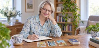 Why the Same Tarot Card Keeps Appearing in Readings Woman reviewing a small tarot spread and journaling her observations